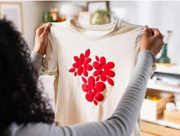 Woman's hand holding a smart phone with a personalized project template pulled up using Cricut's Design Space app