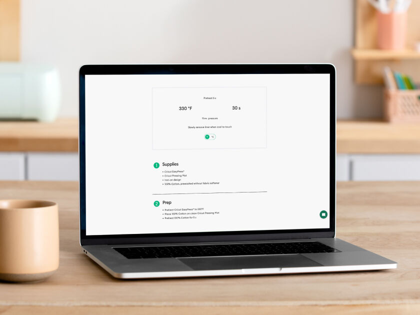 Woman's hands using transfer tape to adhere the blue vinyl onto a small drinking glass