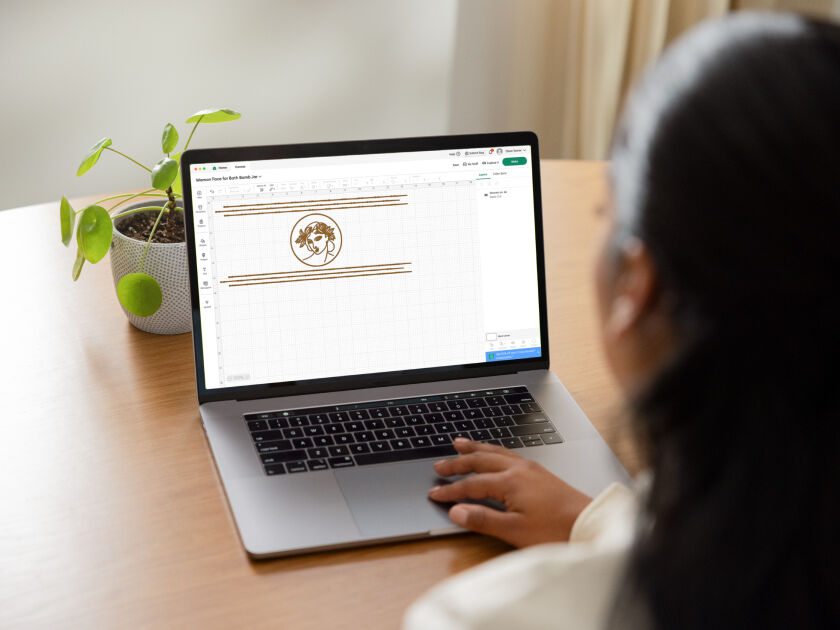 Woman's hand holding a smart phone with a personalized project template pulled up using Cricut's Design Space app