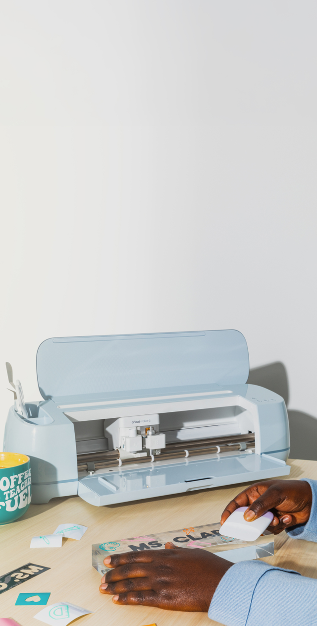 Teacher sitting at her desk using a Cricut Maker 3 machine